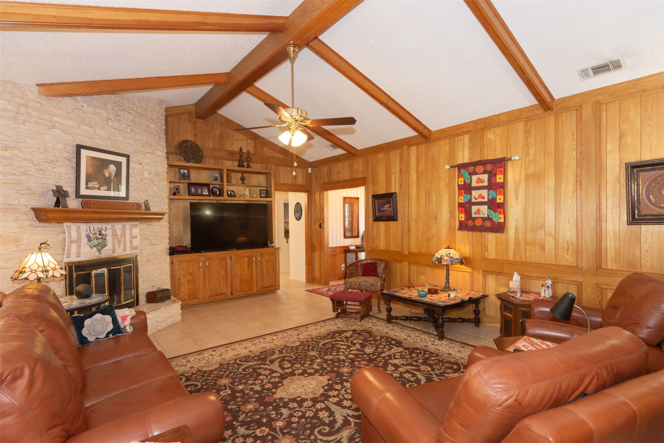 219 Turtle Bend Georgetown, TX 78628 - Photo 11 of 37 Warm wood paneling and a stone fireplace anchor this inviting living room under vaulted ceilings. Also a wall of custom shelving.