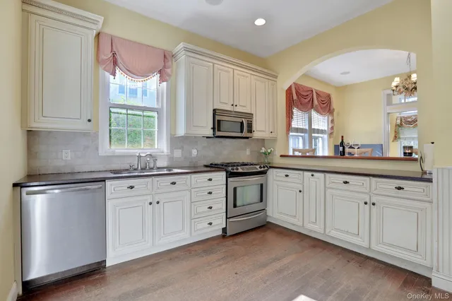 a kitchen with granite countertop white cabinets white stainless steel appliances a sink and a window