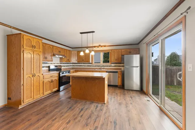 a kitchen with stainless steel appliances a refrigerator and wooden floor