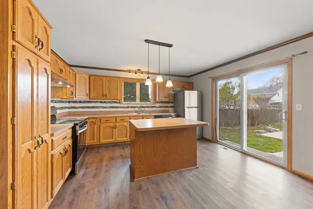 a view of a kitchen with kitchen island a large counter top space and stainless steel appliances