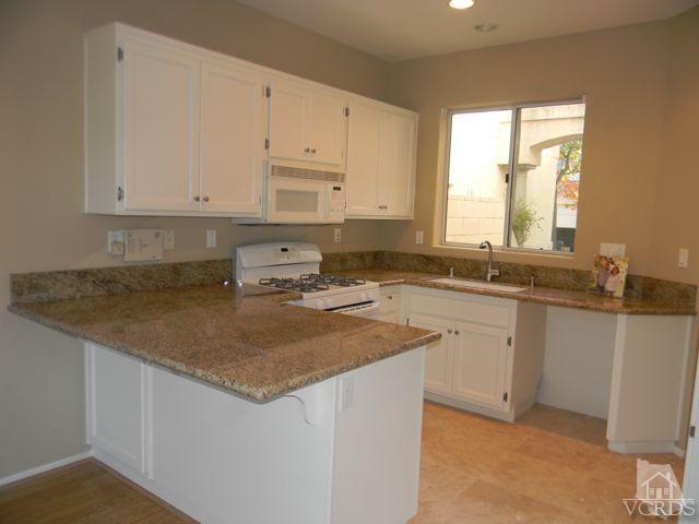 11525 Treeview Court Moorpark, CA 93021 - Photo 3 of 17 a kitchen with granite countertop a sink stove and white cabinets