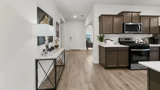 a kitchen with stainless steel appliances a sink dishwasher stove refrigerator and microwave with wooden floor