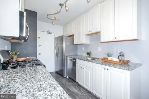 a kitchen with granite countertop a sink a stove and cabinets