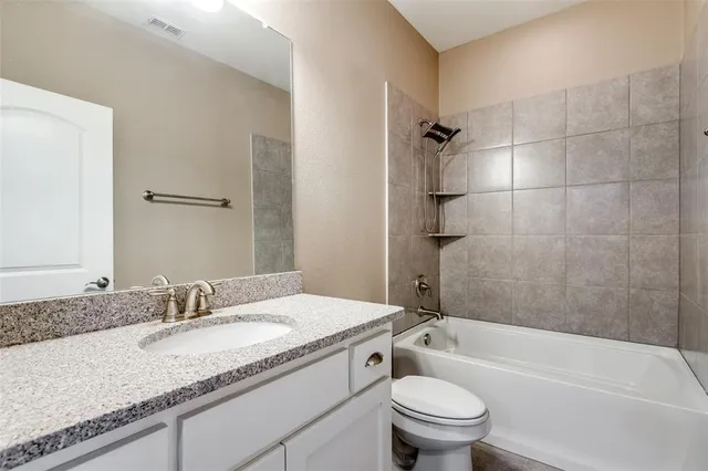 a bathroom with a granite countertop sink a toilet and shower