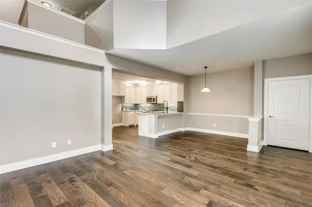 a view of a kitchen with kitchen island a sink wooden floor and a refrigerator
