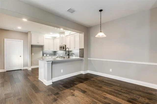 a kitchen with kitchen island a sink dishwasher a stove and white cabinets with wooden floor