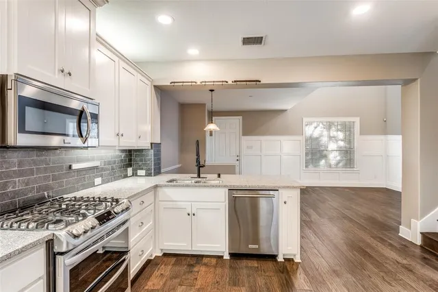 a kitchen with granite countertop a sink stainless steel appliances and cabinets