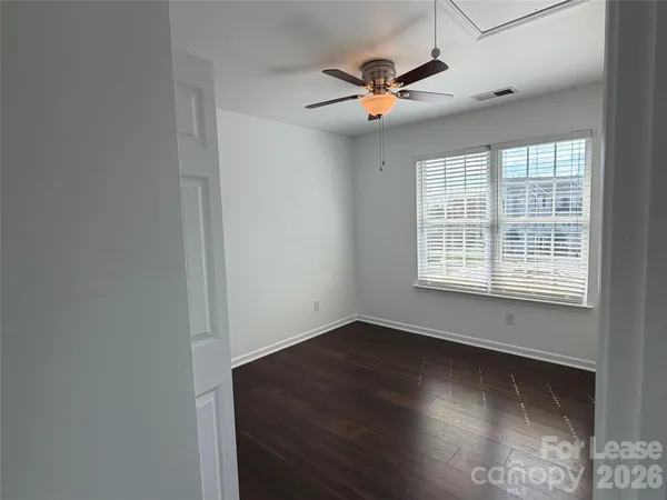 an empty room with wooden floor fan and windows