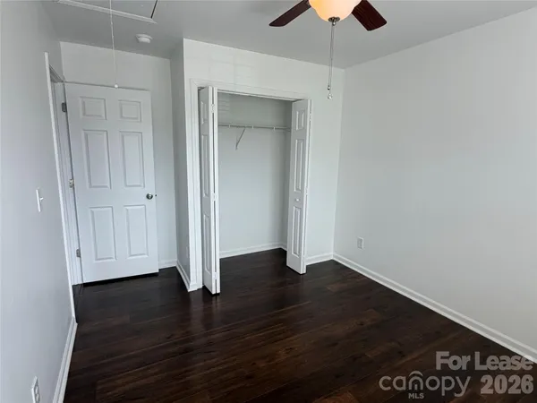 an empty room with wooden floor closet and windows