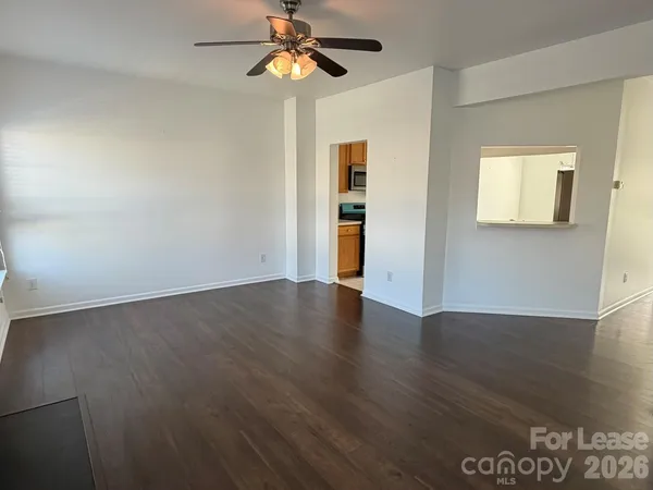 an empty room with wooden floor chandelier fan and windows