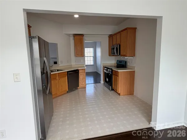 a kitchen with stainless steel appliances granite countertop a stove top oven a sink a refrigerator and dishwasher