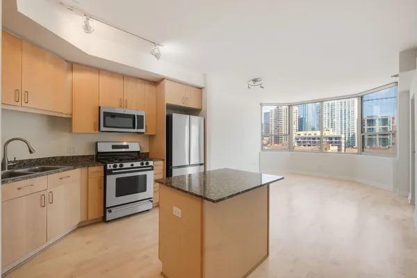 a kitchen with stainless steel appliances granite countertop a refrigerator a stove a sink and a microwave