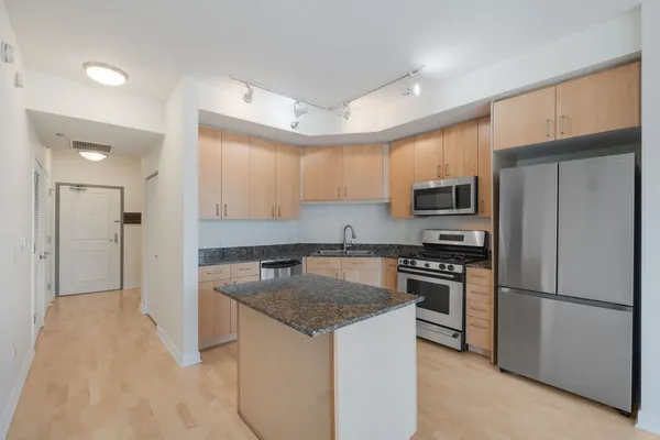 a kitchen with stainless steel appliances granite countertop a refrigerator sink and stove