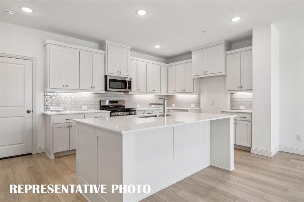 1027 Splitrock Drive Allen, TX 75013 - Photo 5 of 18 a kitchen with kitchen island a sink a stove a microwave and cabinets