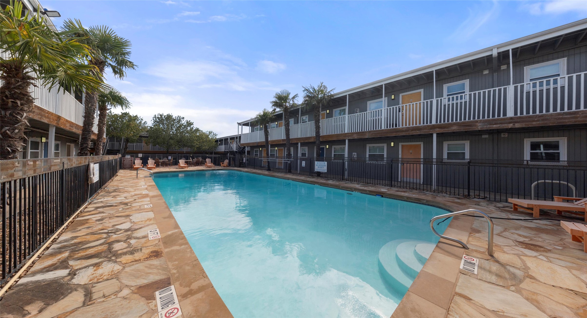 2401 Manor Road, Unit 123 Austin, TX 78722 - Photo 17 of 22 A refreshing outdoor pool with natural stone decking invites relaxation alongside apartment buildings.