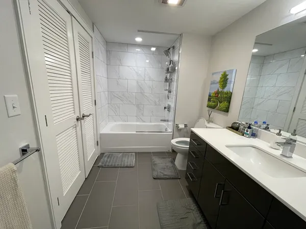 a bathroom with a bathtub shower sink vanity mirror and toilet