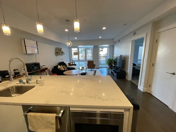 a large kitchen with stainless steel appliances a stove a sink a refrigerator and a refrigerator with wooden floor