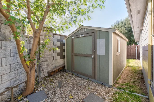 a backyard of a house with wooden fence and large trees