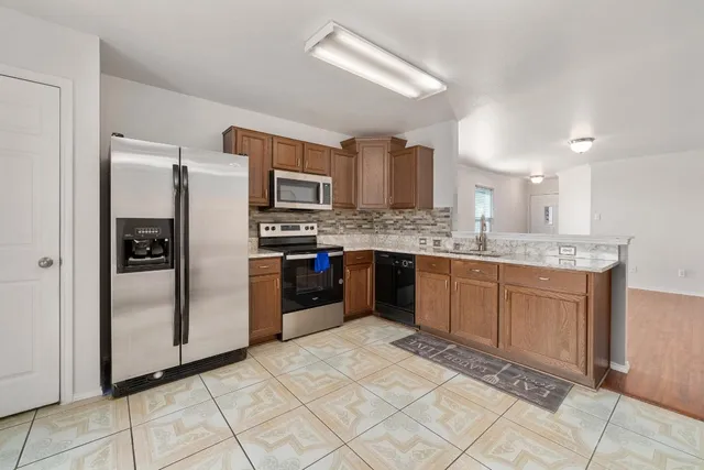 a kitchen with stainless steel appliances granite countertop a refrigerator and a sink