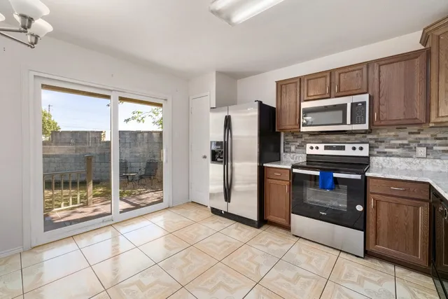 a kitchen with granite countertop a refrigerator and a stove top oven