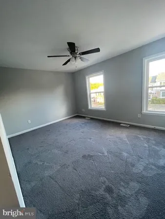 en empty room with windows and ceiling fan