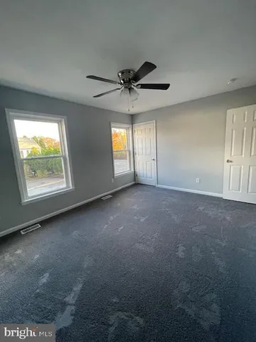 an empty room with windows and ceiling fan