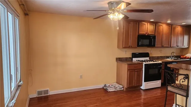 a view of a kitchen with wooden floor and a stove top oven