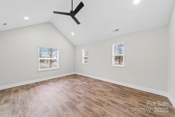 a view of an empty room with a window and wooden floor
