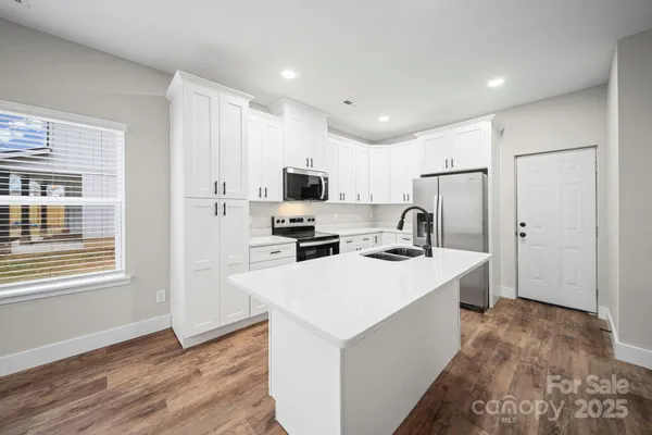 a kitchen with a sink a stove a refrigerator a center island and cabinets