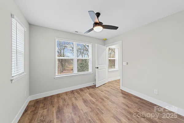 a view of an empty room with wooden floor and a window