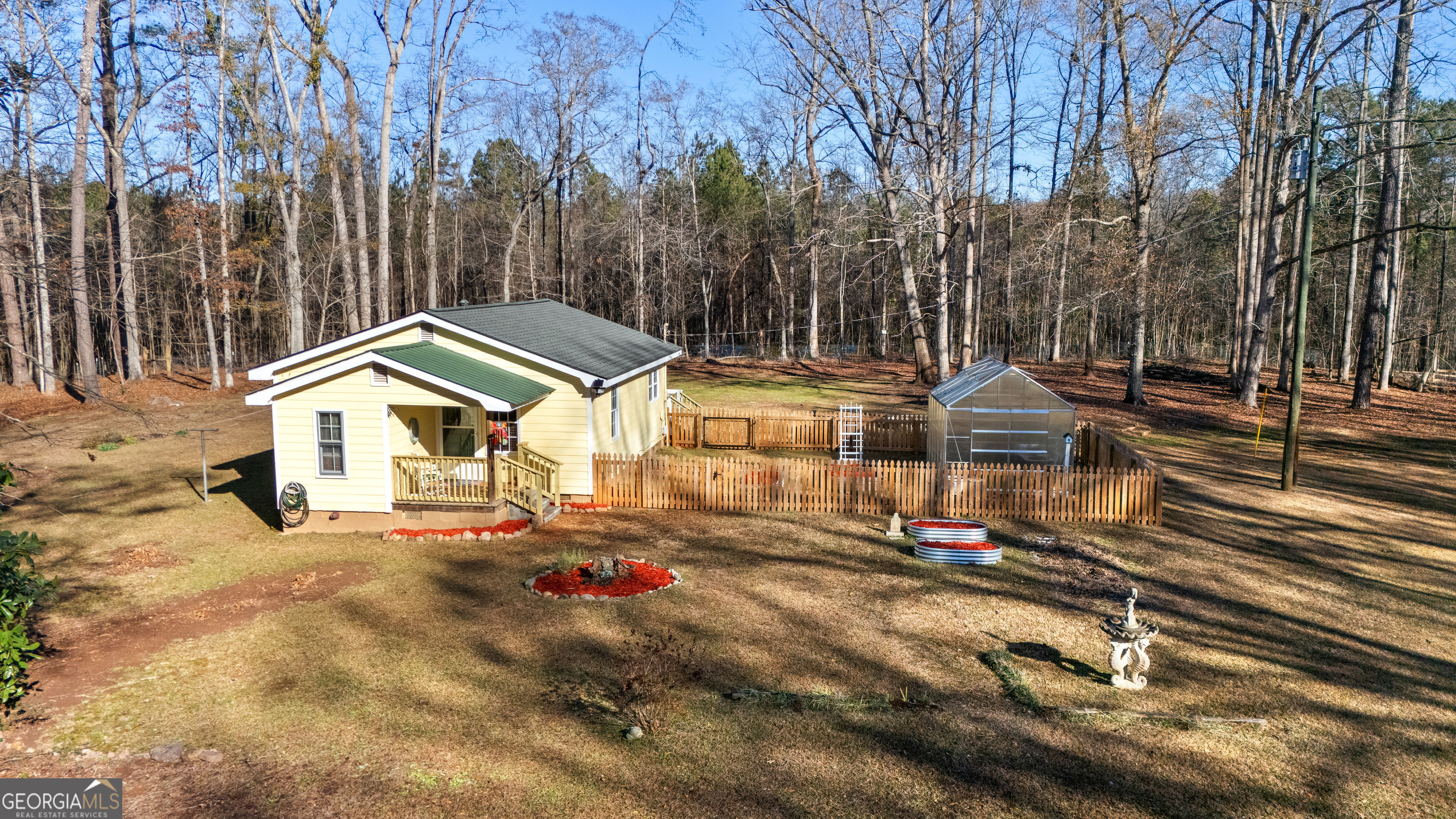 209 Boogers Hill Road Oxford, GA 30054 - Photo 8 of 44 a view of a white house with a yard and lawn chairs under a large tree