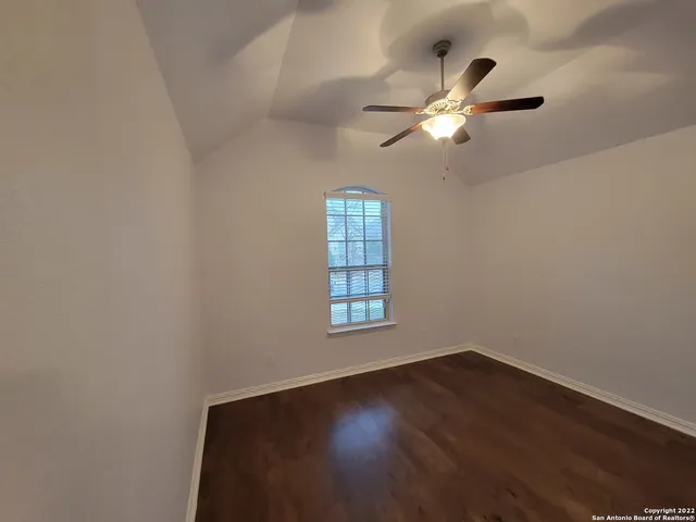 a view of empty room with wooden floor and fan