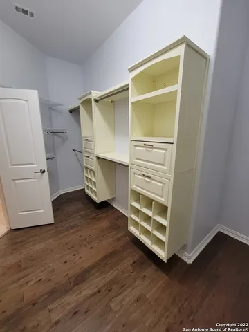 a view of an empty room with wooden floor and a cabinet