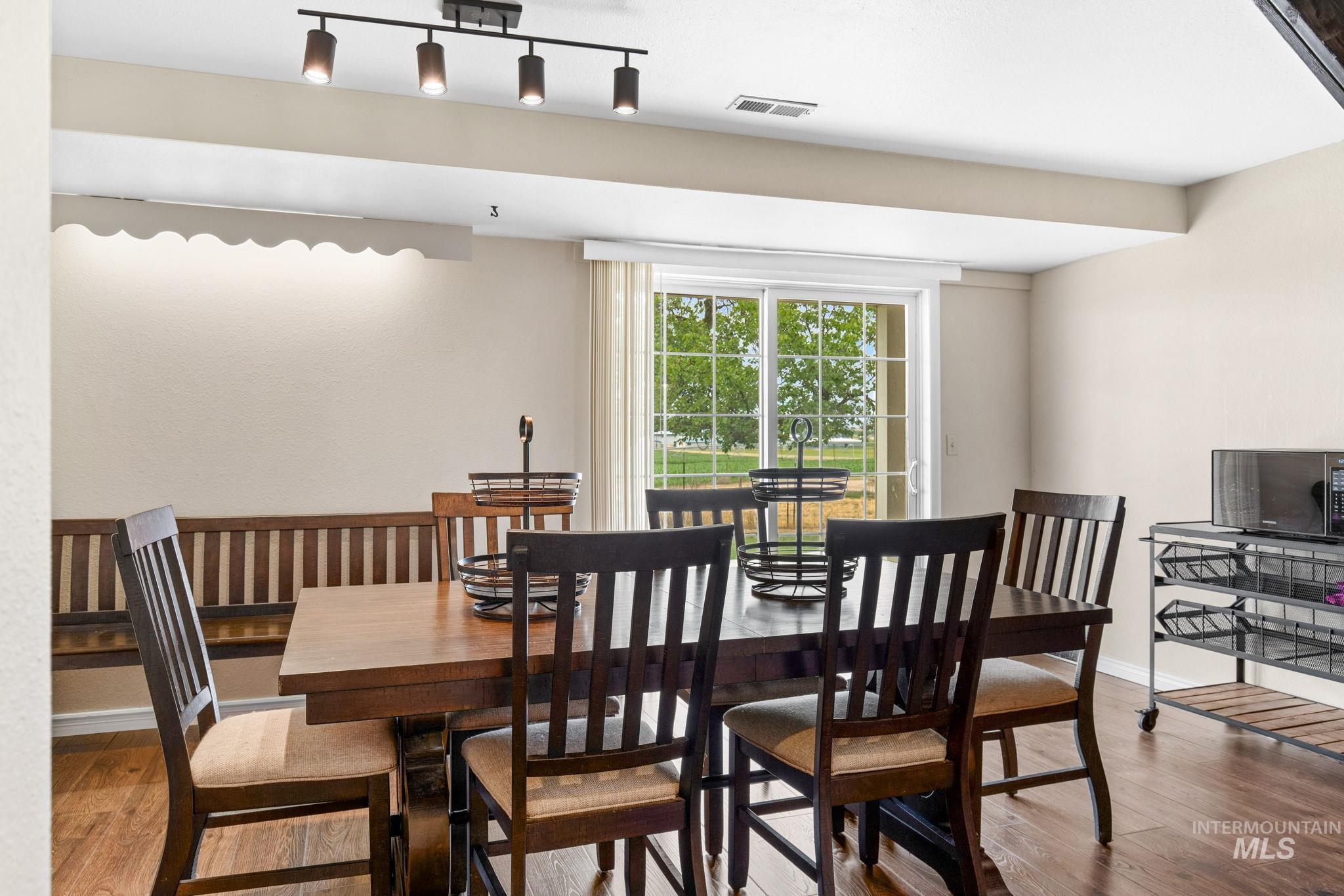 18338 Pride Lane Caldwell, ID 83607 - Photo 9 of 50 Dining area featuring wood-finish flooring, a contemporary track lighting fixture, light-toned walls, and a built-in wooden bench