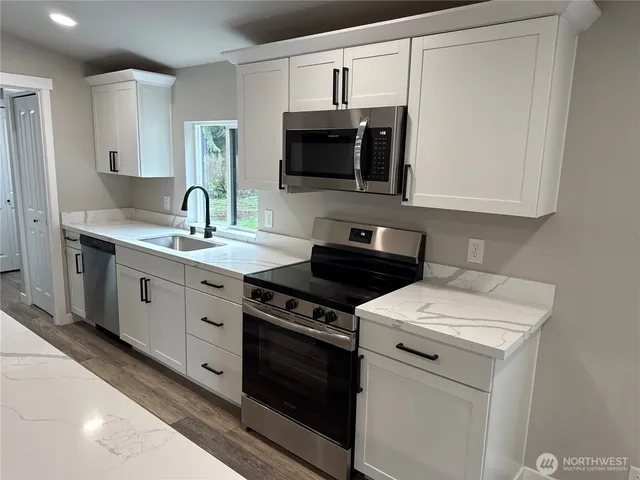 a kitchen with stainless steel appliances a sink stove and microwave