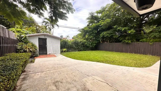 a view of back yard with flower plants and wooden fence