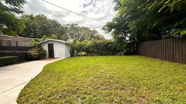 a backyard of a house with plants and large trees