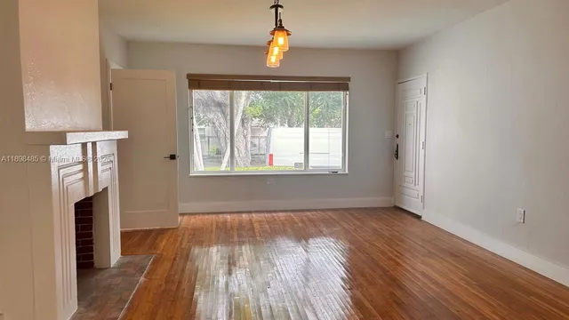 an empty room with wooden floor cabinet and windows
