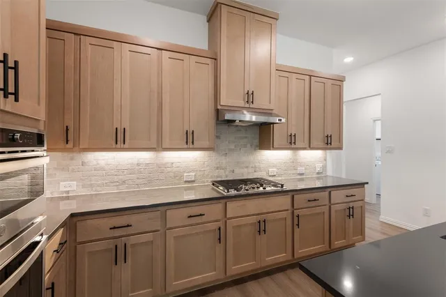 a kitchen with stainless steel appliances granite countertop a sink a stove and cabinets