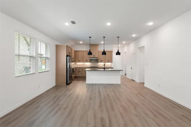 a view of kitchen with kitchen island refrigerator wooden floor and center island