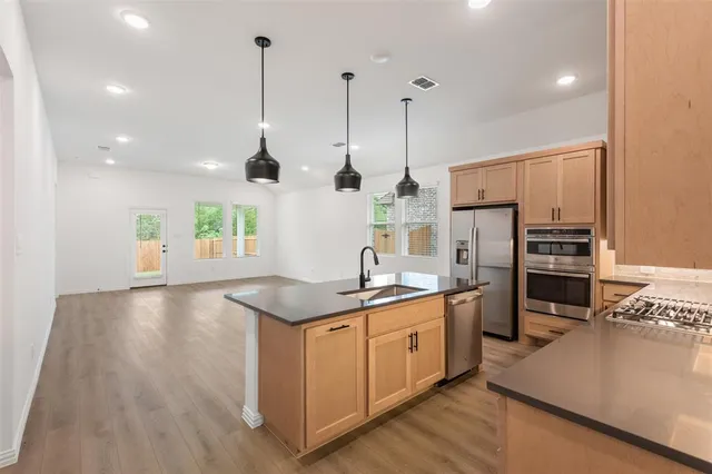 a kitchen with stainless steel appliances granite countertop a sink a stove and a wooden floors