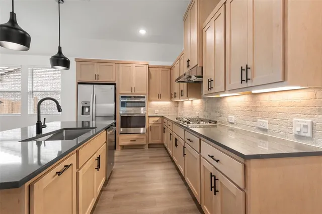 a kitchen with stainless steel appliances granite countertop a sink a stove and a refrigerator