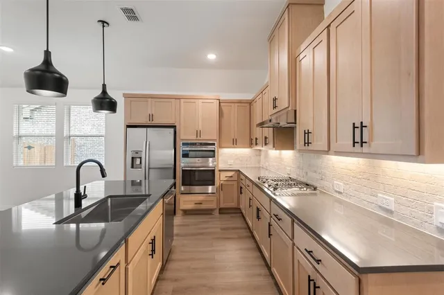 a kitchen with stainless steel appliances granite countertop a sink a stove and refrigerator