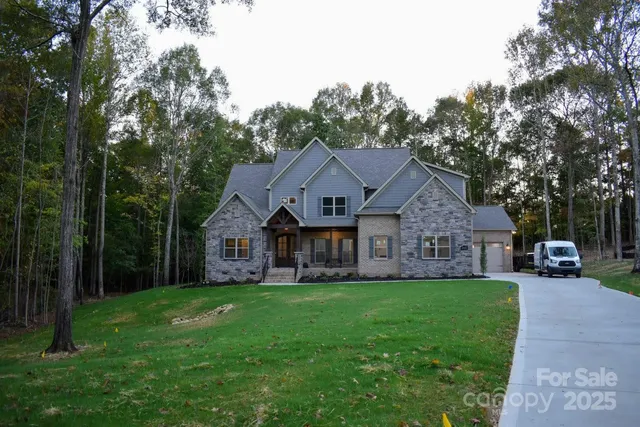 a front view of a house with a garden and trees