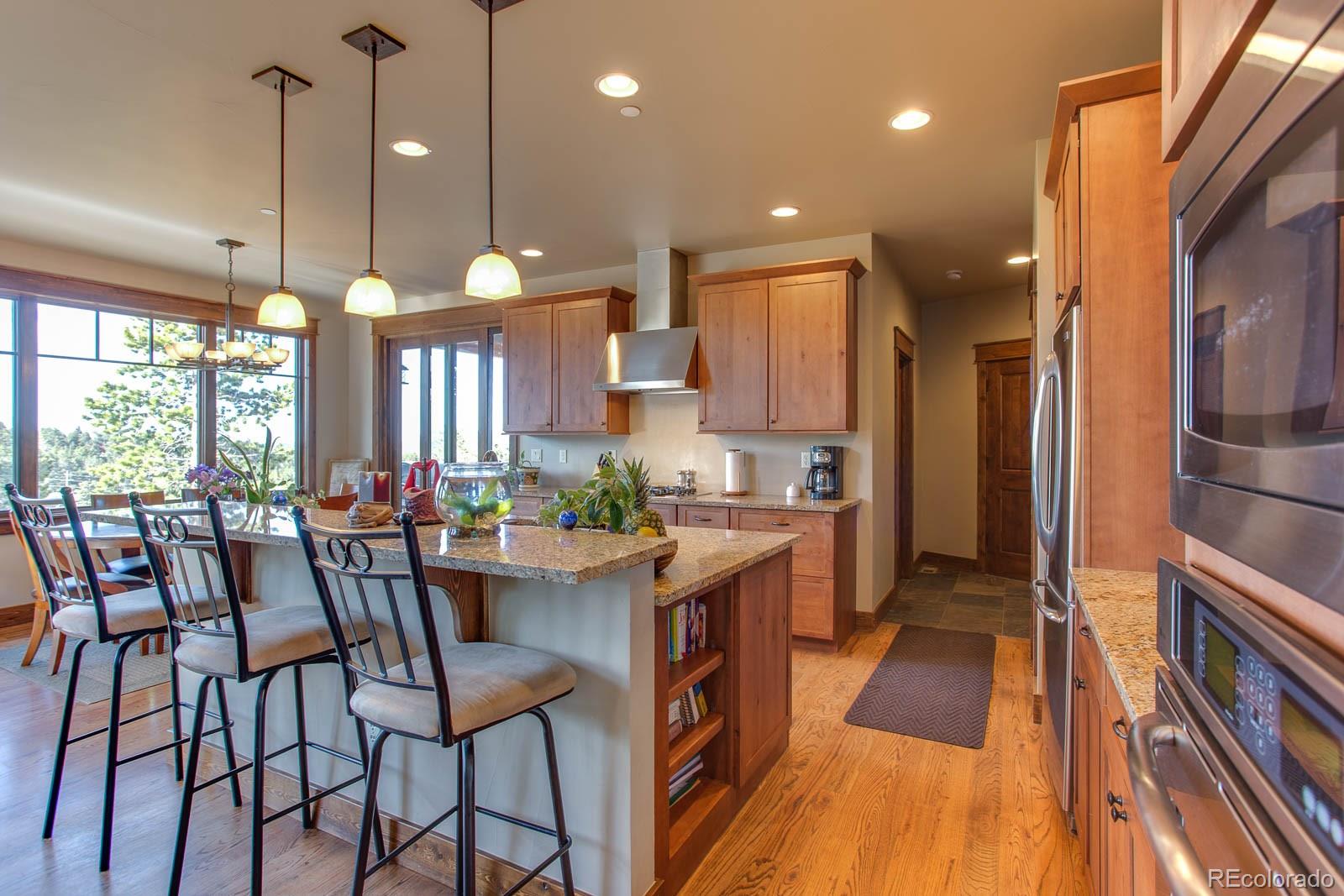 398 Crescent Lake Road Golden, CO 80403 - Photo 4 of 25 a kitchen with stainless steel appliances a dining table chairs and a wooden floor