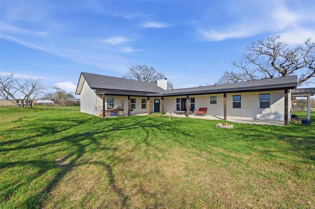 Front of property with a patio, a chimney, and a yard