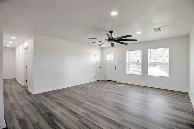 a view of an empty room with wooden floor and a window