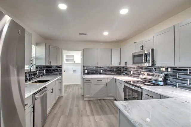 a kitchen with stainless steel appliances granite countertop a stove top oven a sink dishwasher and a refrigerator