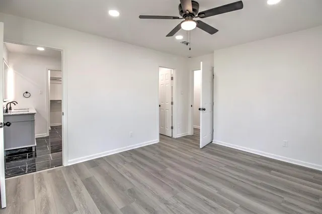 an empty room with wooden floor and ceiling fan