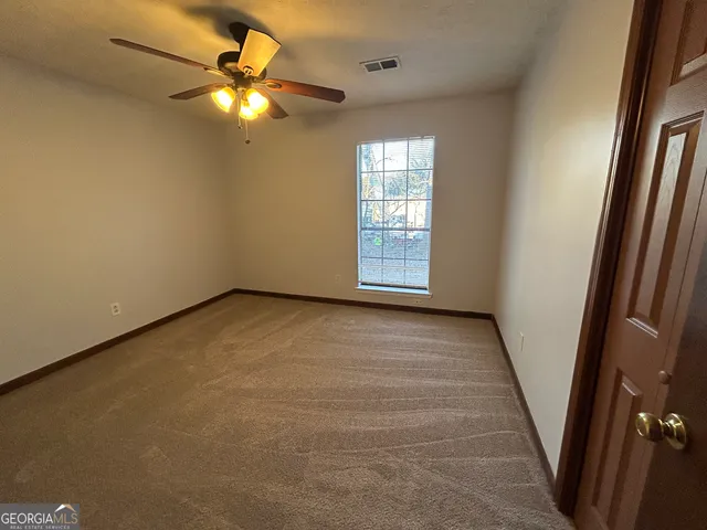 an empty room with windows and fan